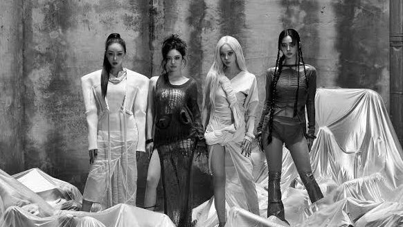 Four women standing among plastic-wrapped bodies in a staged, dramatic setting.