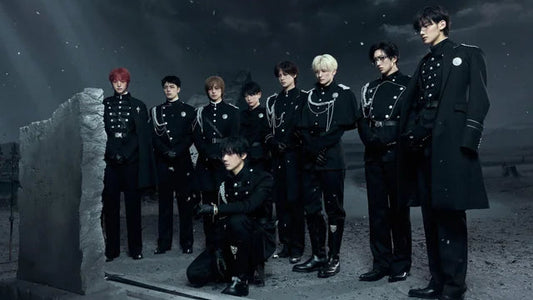 Group of people in formal black attire standing in a dark, outdoor setting with a stone monument.
